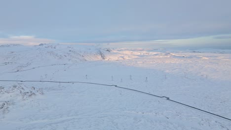 Luftaufnahme-Des-Isländischen-Hochlandes-In-Der-Abenddämmerung,-Schneebedeckte-Berge,-Warmer-Sonnenuntergang-Im-Hintergrund