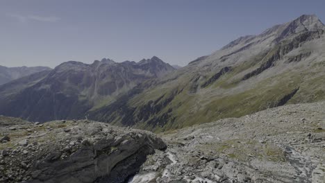 Die-Drohne-Steigt-Anmutig-Herab,-Folgt-Einem-Alpenfluss-Und-Enthüllt-Einen-Wasserfall