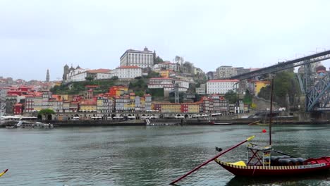 Panoramic-view-of-Porto-old-town-with-Ponte-Luis-I-and-moored-Rabelo-boat-on-rainy-day