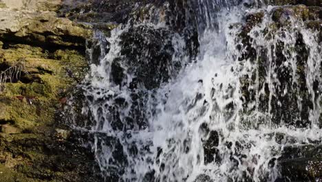 Schnell-Fließender-Wasserfall-Aus-Nächster-Nähe,-Der-Raue-Felsformationen-Hinunterstürzt