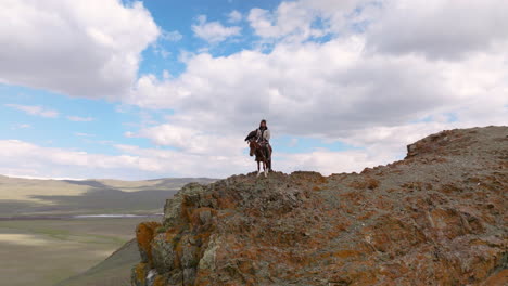 An-Eagle-Hunter-On-Top-Of-The-Cliff-In-Western-Mongolia---Aerial-Drone-Shot