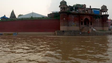 Filmische-Antike-Heilige-Stadt-Varanasi-Indien-Ganges-Kanal-Bootsfahrt-Nordstaat-Menschen-Auf-Stufen-Ghat-Pradesh-Provinz-Landschaft-Grau-Wolkig-Feuer-Rauch-Rechts-Bewegung-Folgen