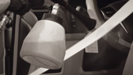 Professional-engineer-wearing-black-gloves-expertly-using-tornado-gun-to-clean-up-car-seat-belt