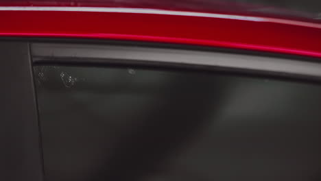 Nahaufnahme-Eines-Ingenieurs,-Der-Schwarze-Handschuhe-Trägt-Und-Ein-Grünes-Mikrofasertuch-Verwendet,-Um-Den-Roten-Seitenfensterspiegel-Eines-Autos-Zu-Reinigen