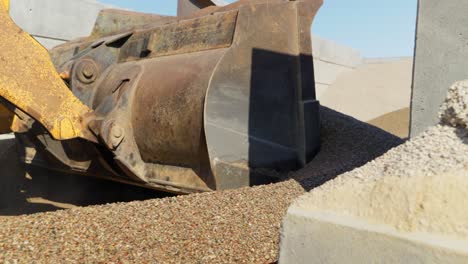 Close-up-on-Liebherr-wheel-loader-bucket-scooping-gravel-on-construction-site