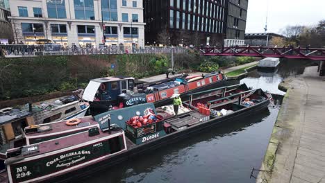 Canal-Boatman-Carrying-Coal-Bag-Supplies-For-Customer-Regents-Canal-In-Kings-Cross-With-Espérance-Bridge-In-Background