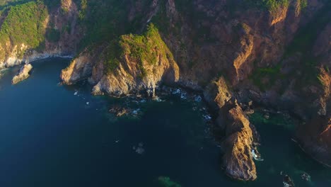 A-drone-view-panning-over-the-rough-mountainous-coast-of-Carrizal-anchorage-near-Mexico-during-golden-hour-in-summer