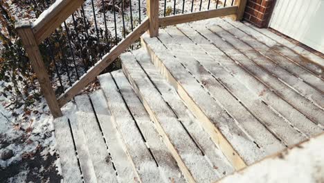 wooden-steps-in-front-of-a-home-lightly-covered-in-snow-during-winter