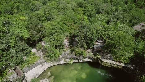 Aerial-view-of-a-cenote-surrounded-by-lush-forest-in-Riviera-Maya