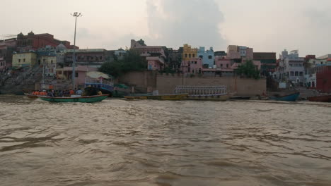 Cinematic-sunset-Ancient-Holy-city-Varanasi-India-Ganges-River-people-gathered-canal-boat-cruise-Northern-State-people-at-Ghat-Pradesh-Province-landscape-gray-cloudy-right-follow-slow-motion-right