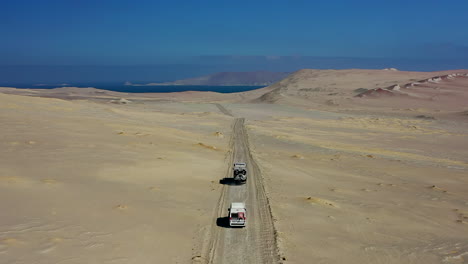 Overlanders-Driving-Sand-Track-Paracas-National-Reserve-Expedition-Truck-Van-Blue-Sky-Pacific-Ocean-Dune