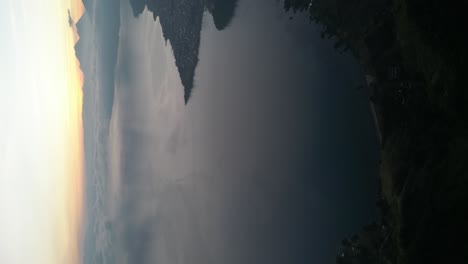 Drohnenporträtansicht-In-Guatemala,-Die-Bei-Sonnenaufgang-An-Einem-Bewölkten-Tag-In-Atitlan-über-Einen-Blauen-See-Fliegt,-Der-Von-Grünen-Bergen-Umgeben-Ist