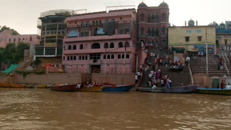 Filmisch-Varanasi-Indien-Ganges-Flusskreuzfahrt-Kanalboot-Nordstaat-Große-Versammlung-Am-Ufer-Alte-Heilige-Stadt-Ghat-Pradesh-Provinz-Landschaft-Grau-Wolkig-Heilig-Schlammig-Braun-Nachmittag-Sonnenuntergang-Folgen