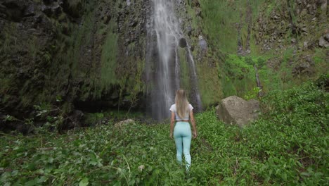 Woman-hiking-in-lush-tropical-valley-with-tall-Agua-D'Alto-waterfall