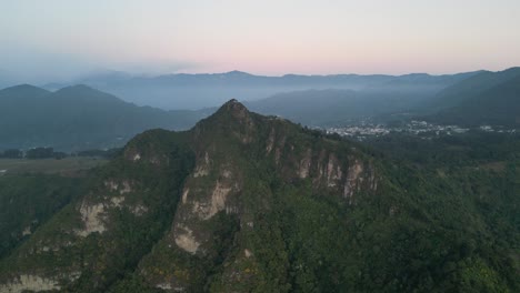 Vista-De-Drones-En-Guatemala-Volando-Frente-A-Una-Montaña-Verde-Rodeada-De-Volcanes-En-Un-Día-Nublado-En-Atitlán