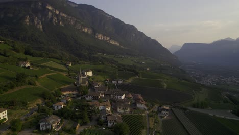 Un-Dron-Captura-El-Pueblo-De-Pinzano-En-Tirol-Del-Sur-Durante-La-Hora-Dorada,-Proyectando-Un-Brillo-Cálido-Y-Encantador.