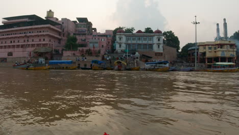 Filmisch-Varanasi-Indien-Ganges-Kanal-Bootsfahrt-Nordstaat-Menschen-Versammeln-Sich-Auf-Stufen-Einäscherung-Antike-Heilige-Stadt-Ghat-Pradesh-Provinz-Landschaft-Grau-Wolkig-Feuer-Rauch-Rechte-Bewegung