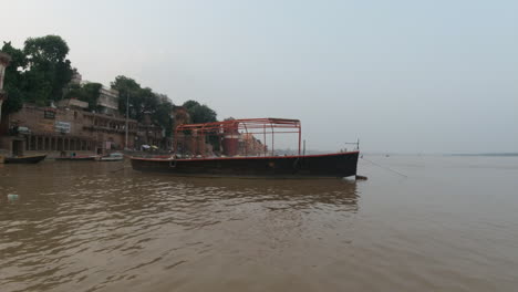 Filmischer-Sonnenuntergang,-Malerischer-Bootsschwenk-Nach-Rechts,-Alte-Heilige-Stadt-Varanasi,-Indien,-Ganges-Fluss,-Kanal-Bootsfahrt,-Nordstaat,-Menschen-In-Der-Provinz-Ghat-Pradesh,-Landschaft,-Grau-Bewölkt