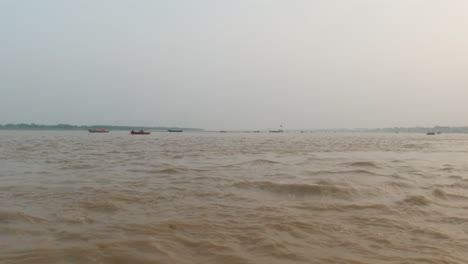 Cinematic-Ganges-still-calm-muddy-brown-River-cruise-chowk-canal-boat-Varanasi-Northern-India-State-Ancient-Holy-city-Khidkiya-Ghat-Pradesh-Provinc-landscape-gray-cloudy-afternoon-pan-left-motion
