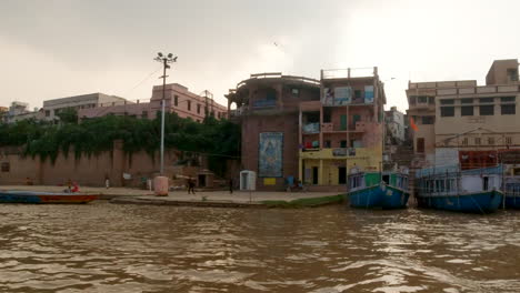 Filmisch-Varanasi-Indien-Ganges-Vögel-Fliegender-Chow-Auf-Kreuzfahrt-Kanalboot-Nordstaat-Alte-Heilige-Stadt-Provinz-Ghat-Pradesh-Landschaft-Grau-Wolkig-Heilig-Schlammig-Braun-Nachmittagssonnenuntergang-Folgen-Sie-Links
