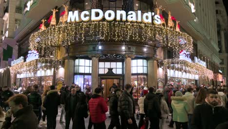 Pedestrians-are-seen-in-front-of-the-American-multinational-fast-food-hamburger-restaurant-chain,-McDonald's,-decorated-with-Christmas-lights