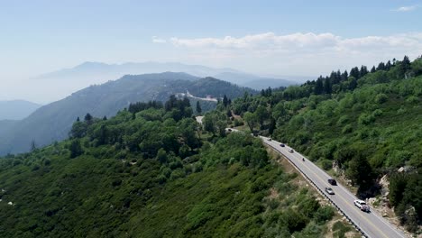 Eine-4K-Tracking-Drohnenaufnahme-Von-Autos,-Die-Auf-Einer-Straße-Fahren,-Die-Hoch-Oben-Auf-Einem-Gebirgspass-In-Der-Nähe-Des-Angeles-National-Forest-Und-Des-Berges-Gefunden-Wurde