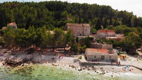 Aerial-rising-shot-on-people-relaxing-on-the-coast-of-the-small-Vrnik-island-near-Korcula,-Croatia