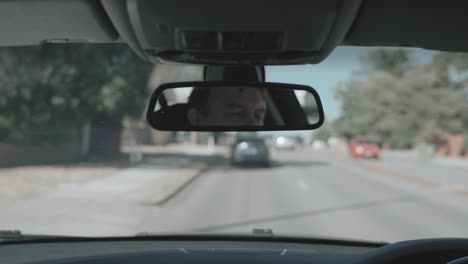 Spiegelung-Des-Gesichts-Eines-Mannes-Im-Spiegel-Eines-Fahrers,-Während-Er-Ein-Auto-Fährt