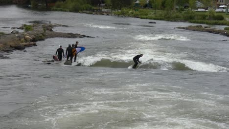 Man-surfing-in-whitewater-rapids-in-the-middle-of-a-river