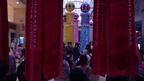 Gente-En-Arcade-Caminando-Entre-Serpentinas-De-Papel-Decorativas-Durante-El-Festival-De-Tanabata