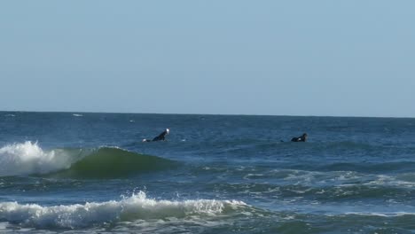 Surfer-In-Neoprenanzügen-Reiten-Auf-Den-Wellen-An-Der-Pause-Vorbei-Und-Suchen-Nach-Einer-Welle,-Auf-Der-Sie-Von-Links-Nach-Rechts-Reiten-Können