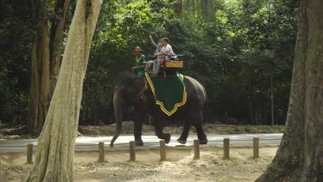 Slow-motion-footage-of-tourists-riding-elephants-and-vehicles-around-the-Bayon-temple-in-Angkor,-Siem-reap,-Cambodia