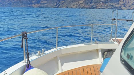 Motor-boat-breaking-through-waves,-view-of-deck-and-rugged-coast-of-Tenerife
