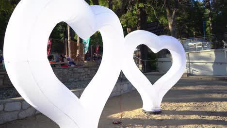 Inflatable-hearts-displayed-on-the-beach-with-people-walking-in-the-background