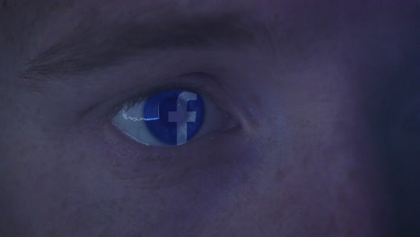 Extreme-Nahaufnahme-Des-Auges-Eines-Jungen-Mannes,-Der-Spät-In-Der-Nacht-Auf-Das-Facebook-Logo-Starrt