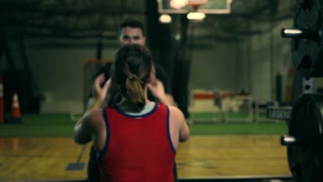 Man-is-throwing-a-ball-to-a-woman-during-exercising-at-the-gym