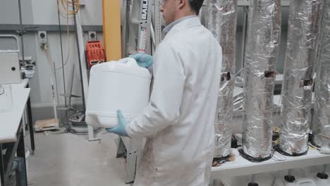 Wissenschaftler-Füllen-Plastikbehälter-Mit-Blauer-Flüssigkeit-In-Einem-Labor