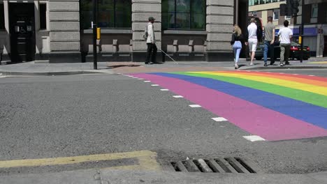 People-at-Rainbow-street-pedestrian-crossing-at-intersection-in-London-for-gay-pride,-pride-month,-eye-level-shot,-static-camera,-day-,real-time