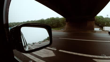 View-and-rear-view-mirror-of-a-car-driving-along-a-motorway-in-the-UK