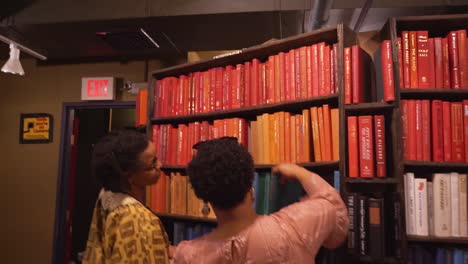 Dos-Mujeres-Mirando-Libros-En-Una-Librería-Antigua.