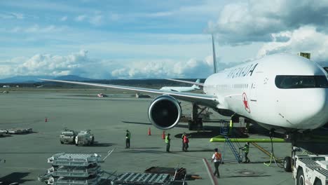 Air-Canada-plane-parked-at-the-gate-with-runway-workers-talking-and-working