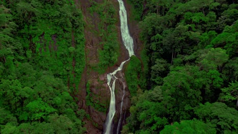 Pan-Aerial-shot-of-a-tall-waterfall-in-the-dense-Costa-Rican-jungle