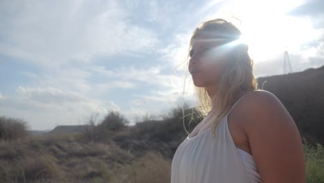 Eine-Schöne-Frau-In-Einem-Weißen-Kleid,-Die-In-Zeitlupe-Mit-Sonnenstrahlen-Durch-Die-Hügel-Griechenlands-Spaziert