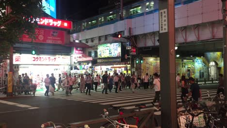 People-crossing-the-road-in-Tokyo,-Japan-at-night-time