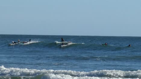 Mehrere-Surfer-In-Neoprenanzügen-Versuchen,-Auf-Derselben-Welle-Aufzustehen.-Die-Welle-Schwenkt-Von-Rechts-Nach-Links