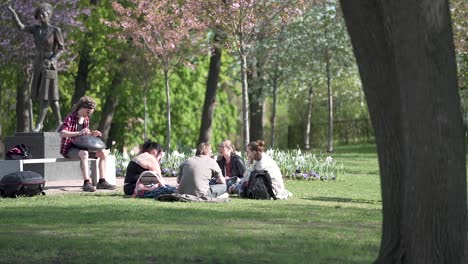 Eine-Gruppe-Von-Menschen-Versammelte-Sich-Zu-Einem-Picknick,-Während-Eine-Person-Im-Park-Des-Königlichen-Palastes-Von-Oslo,-Norwegen,-Eine-Hängetrommel-Spielte