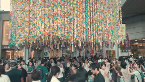 Gente-En-Una-Calle-Concurrida-Caminando-Entre-Serpentinas-De-Papel-Decorativas-Durante-El-Festival-De-Tanabata-En-Cámara-Lenta