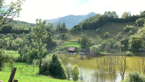 Countryside-view-in-a-village-in-Rosia-Montana-with-old-traditional-Romanian-houses-surrounded-by-a-mud-lake-and-green-forests-on-a-sunny-bright-day
