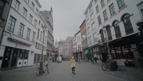Walking-Along-a-Cobblestone-Street-in-Antwerp,-Shops,-Off-Season,-POV