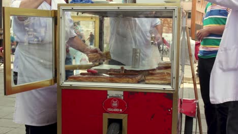 Street-food-cart-in-Istanbul-with-seller-cutting-piece-of-borek-for-customer